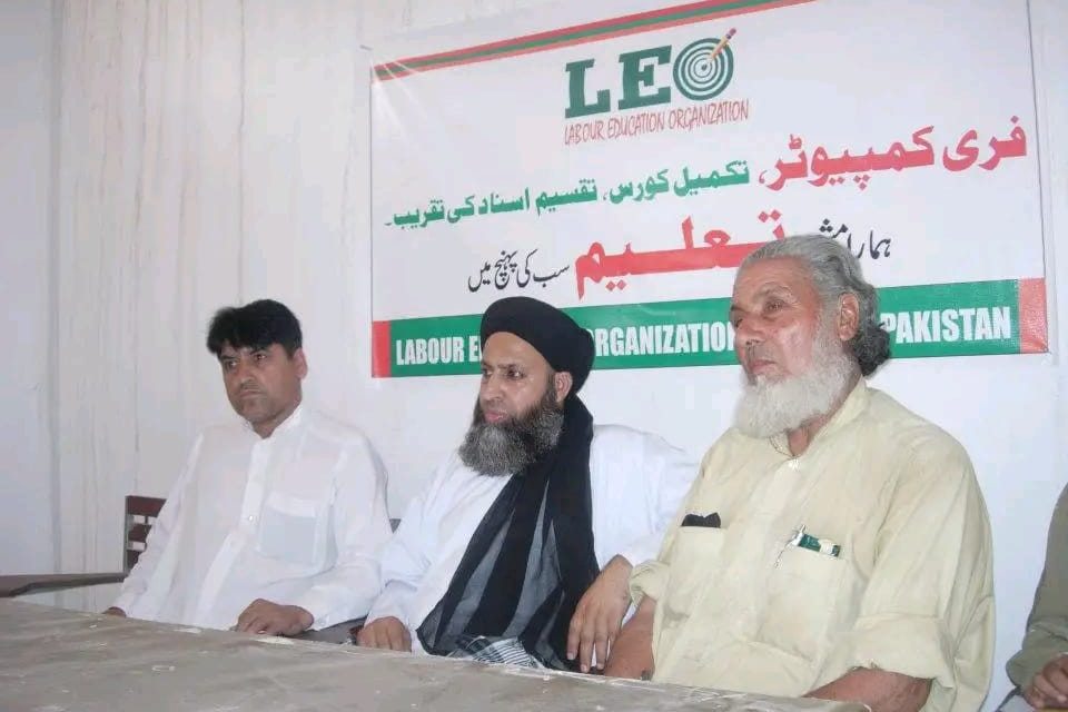 Guests seated at the ceremony table beneath a Labour Education Organization banner for a free computer course certificate distribution