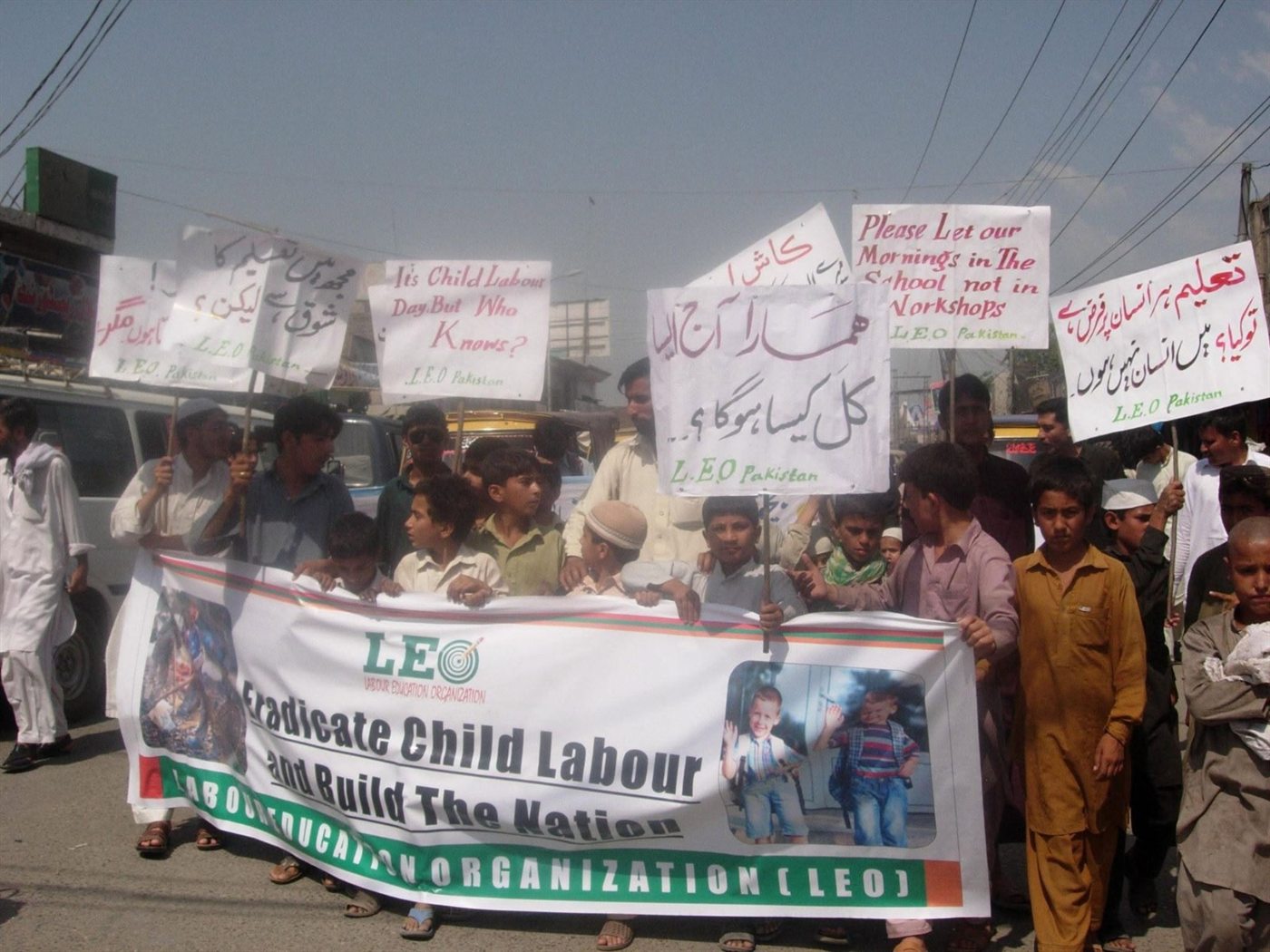 Marchers behind a Labour Education Organization banner reading Eradicate Child Labour and Build The Nation, with hand-lettered placards about schooling