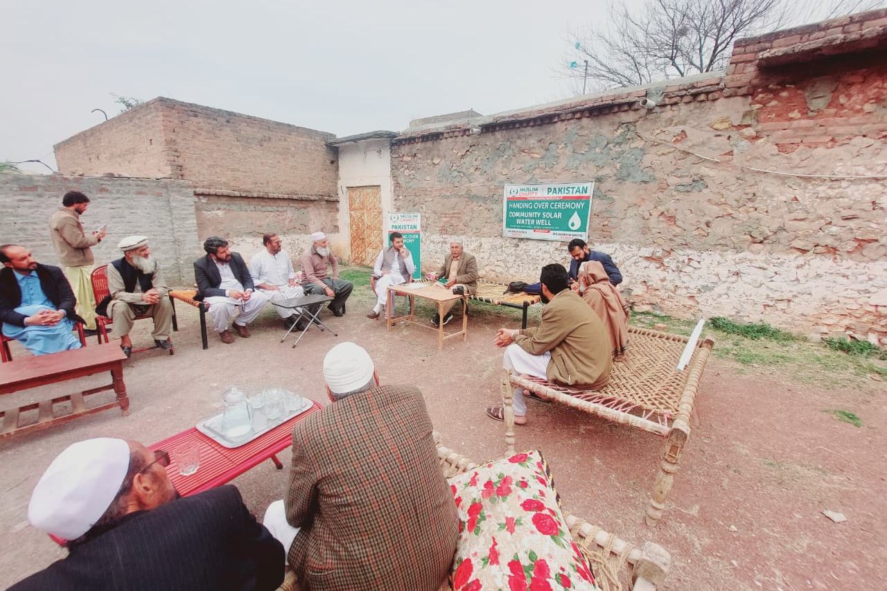 Village elders and LEO representatives seated in a walled courtyard at the Dag Ismail Khel handover meeting