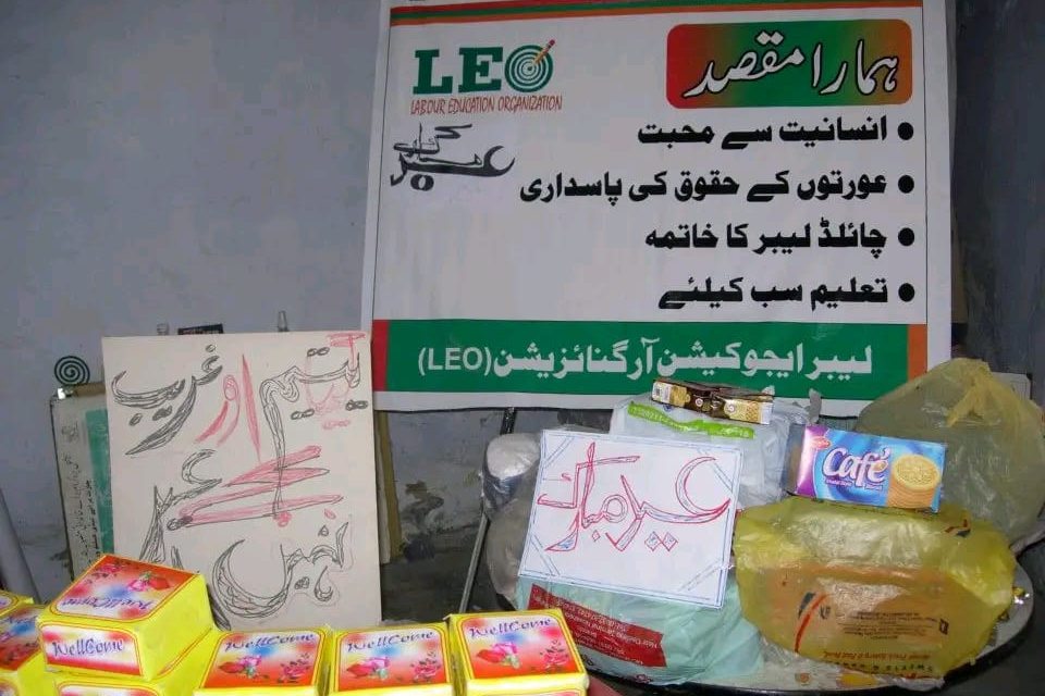 Eid gift packets laid out beneath a LEO banner listing the organization's aims in Urdu