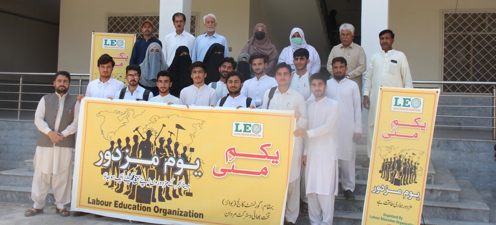 Students and staff at Government Degree College Takht Bhai holding a Labour Education Organization banner for International Workers Day