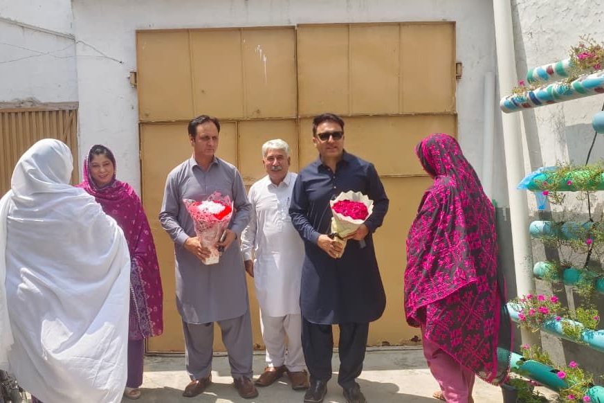 LEO team members welcoming visitors with flowers at the entrance to the organization's premises in Mardan