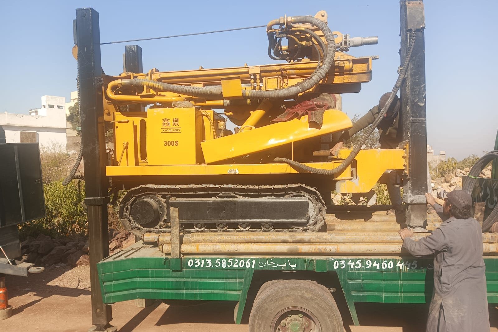 Close view of a drilling rig being positioned on its carrier truck before boring a community water well